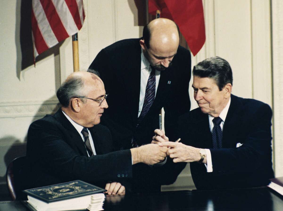 FILE - In this Dec. 8, 1987 file photo U.S. President Ronald Reagan, right, and Soviet leader Mikhail Gorbachev exchange pens during the Intermediate Range Nuclear Forces Treaty signing ceremony in the White House East Room in Washington, D.C. Gorbachev's translator Pavel Palazhchenko stands in the middle. Trump's announcement that the United States would leave the Intermediate-Range Nuclear Forces, or INF, treaty brought sharp criticism on Sunday Oct. 21, 2018, from Russian officials and from former Soviet President Mikhail Gorbachev, who signed the treaty in 1987 with President Ronald Reagan. (AP Photo/Bob Daugherty, File)