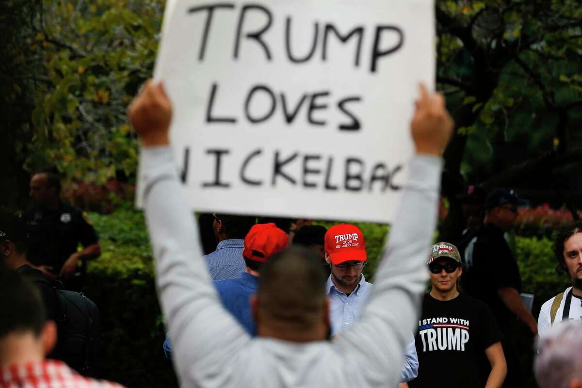 A protester holds a sign across from President Donald Trump supporters outside the Toyota Center where Trump is holding a rally Monday Oct. 22, 2018 in Houston.