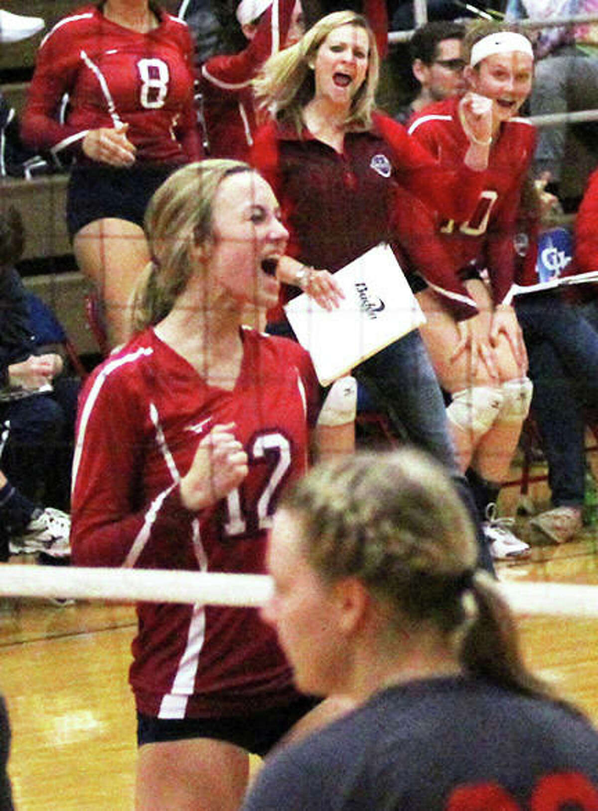 Carlinville’s Adriann Welte (12) and Cavaliers coach Kaitie Hammann (back) celebrate a point during a Macoupin County Tourney match against Staunton on Oct. 6 in Carlinville. Both the Cavs and the Bulldogs won Class 2A regional semifinals on Tuesday.