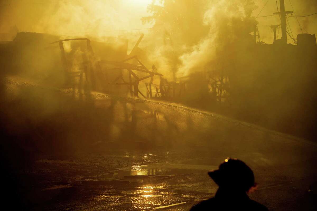 A firefighter passes the smoldering remains of a warehouse in Oakland on Tuesday, October 10, 2018. The blaze destroyed a block-long warehouse occupied by the George E. Masker Painting Company at 72nd Avenue and Hawley Street in Oakland.
