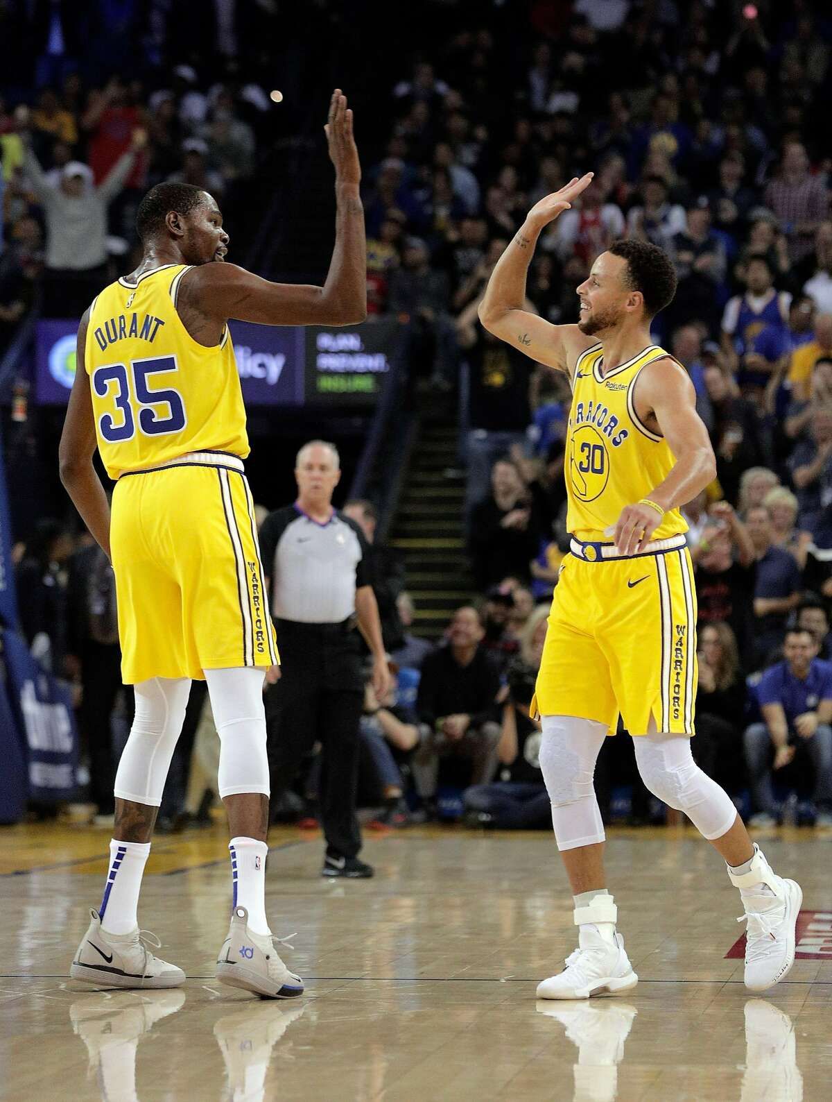 Stephen Curry (30) and Kevin Durant (35) high five after Curry hit one of several three pointers in the first half as the Golden State Warriors played the Washington Wizards at Oracle Arena in Oakland on Wednesday, Oct. 24, 2018. 