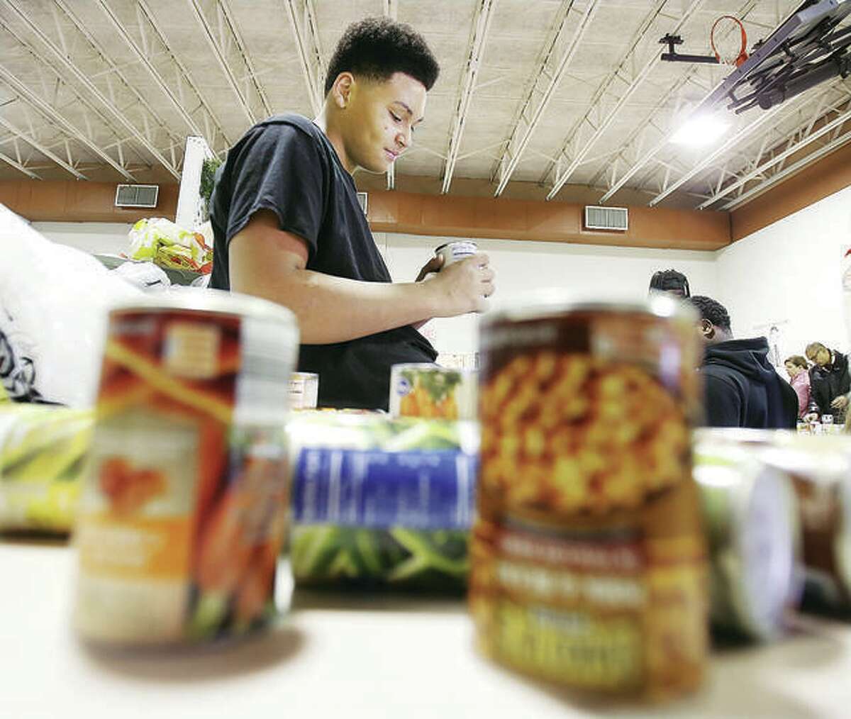 Roxana High School student Kyler Clark-Bowens helps check the expiration dates of canned goods during last year’s Community Christmas drive.