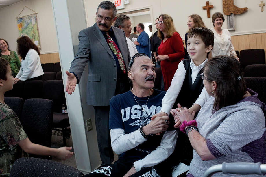 Gunny Macias and his wife, Jennifer, meet with fellow parishioners a few months after his return to the church. Seriously wounded in the attack, Gunny, a Marine veteran, used a walker and still was connected to tubes on his first visit back. “I felt all the embarrassment, and the pain, and all that stuff just went away when I got to church. Just went away, and melted away, and it still does." / Lisa Krantz/San Antonio Express-News