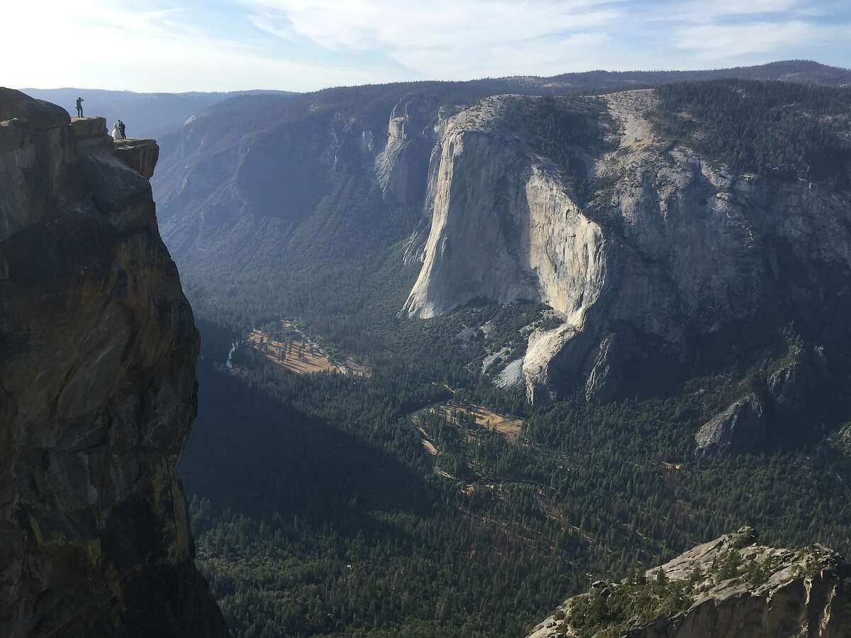 FILE - In this Sept. 27, 2018 file photo a wedding couple are seen being photographed at Taft Point in California's Yosemite National Park. A Yosemite National Park official says two visitors have died in a fall from the popular overlook. Park rangers are trying to recover the bodies of a man and a woman Thursday, Oct.25, 2018. He didn't say when the couple fell from Taft Point, which is at an elevation of 7,500 feet. Gediman says the deaths are being investigated and offered no other information. (AP Photo/Amanda Lee Myers,File)