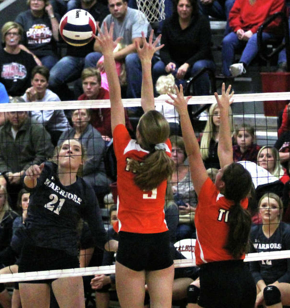 Calhoun’s Holly Baalman (left) hits over the block of Greenfield’s Hailey Driscoll (middle) and Carly Gregory.