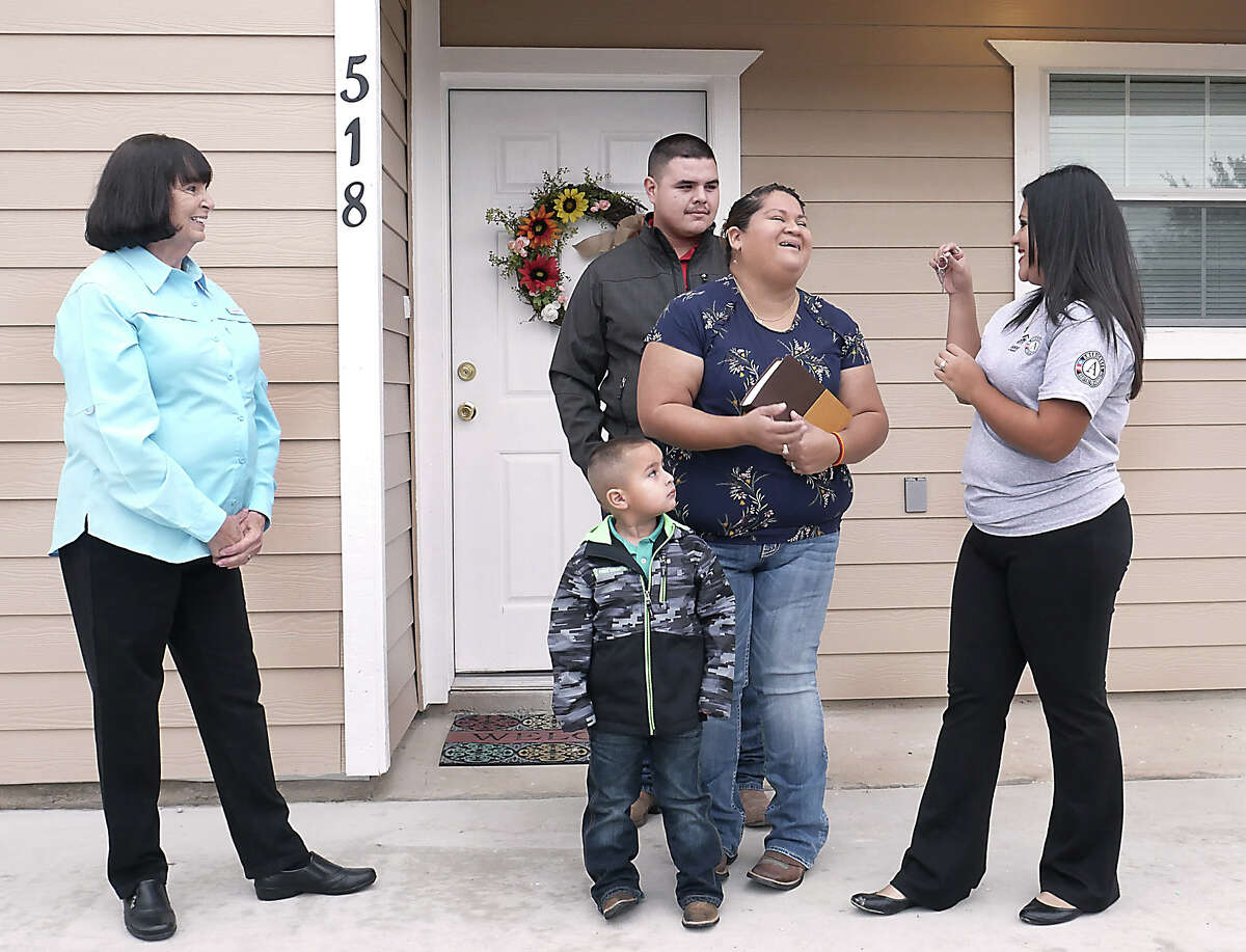 Erica de Luna, her husband Osiel Gutierrez and son Osiel Jr., react as they are presented with the keys to their new home by Habitat for Humanity/AmeriCorps Construction Crew Leader, Kimberly Mata, Thursday, October 25, 2018. Habitat for Humanity Laredo Executive Director Carol Sherwood looks on. The homeowners have been working hard to fulfill all of the requirements for Habitat Home Ownership, including putting in over 500 sweat equity hours.