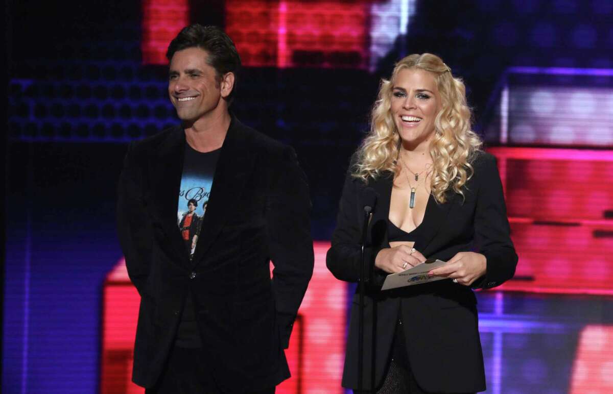 John Stamos, left, and Busy Phillips present the award for favorite male soul/R&B artist at the American Music Awards on Tuesday, Oct. 9, 2018, at the Microsoft Theater in Los Angeles. (Photo by Matt Sayles/Invision/AP)