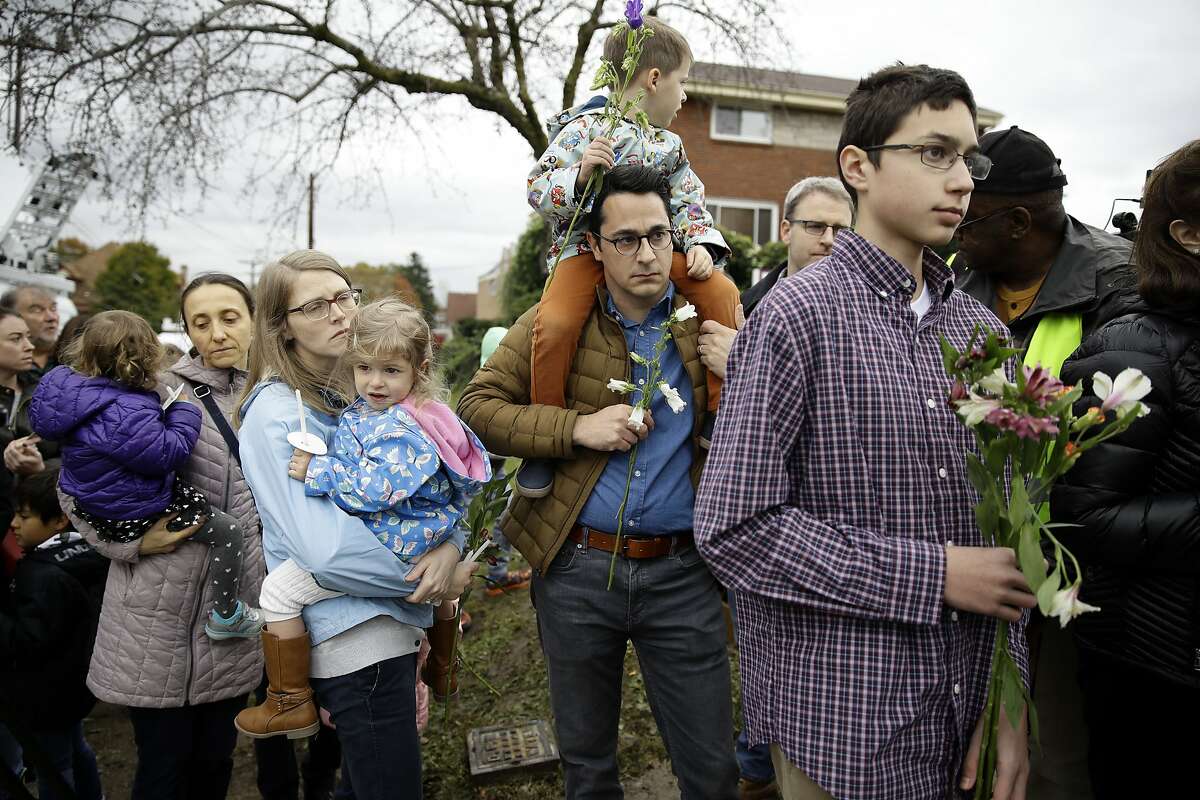 People wait their turn to place flowers at the Tree of Life Synagogue in Pittsburgh, Sunday, Oct. 28, 2018. Robert Bowers, the suspect in the mass shooting at the synagogue, expressed hatred of Jews during the rampage and told officers afterward that Jews were committing genocide and he wanted them all to die, according to charging documents made public Sunday.(AP Photo/Matt Rourke)