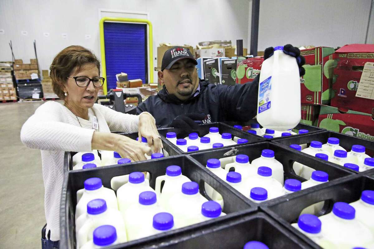 Food insecurity is one of the four social determinants of health. Here, Carey Lenss examines product with Steven Gutierrez after pallets of Oak Farms milk are unloaded at the San Antonio Food Bank on October 31.