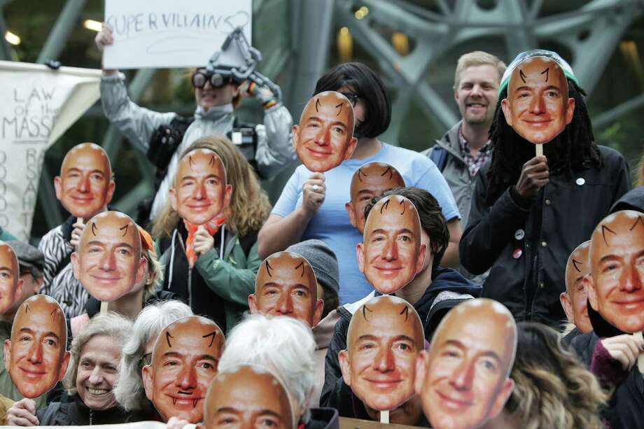 Dozens of protesters brandish masks of Jeff Bezos as they gather in downtown to denounce Amazon for providing their facial recognition software, 