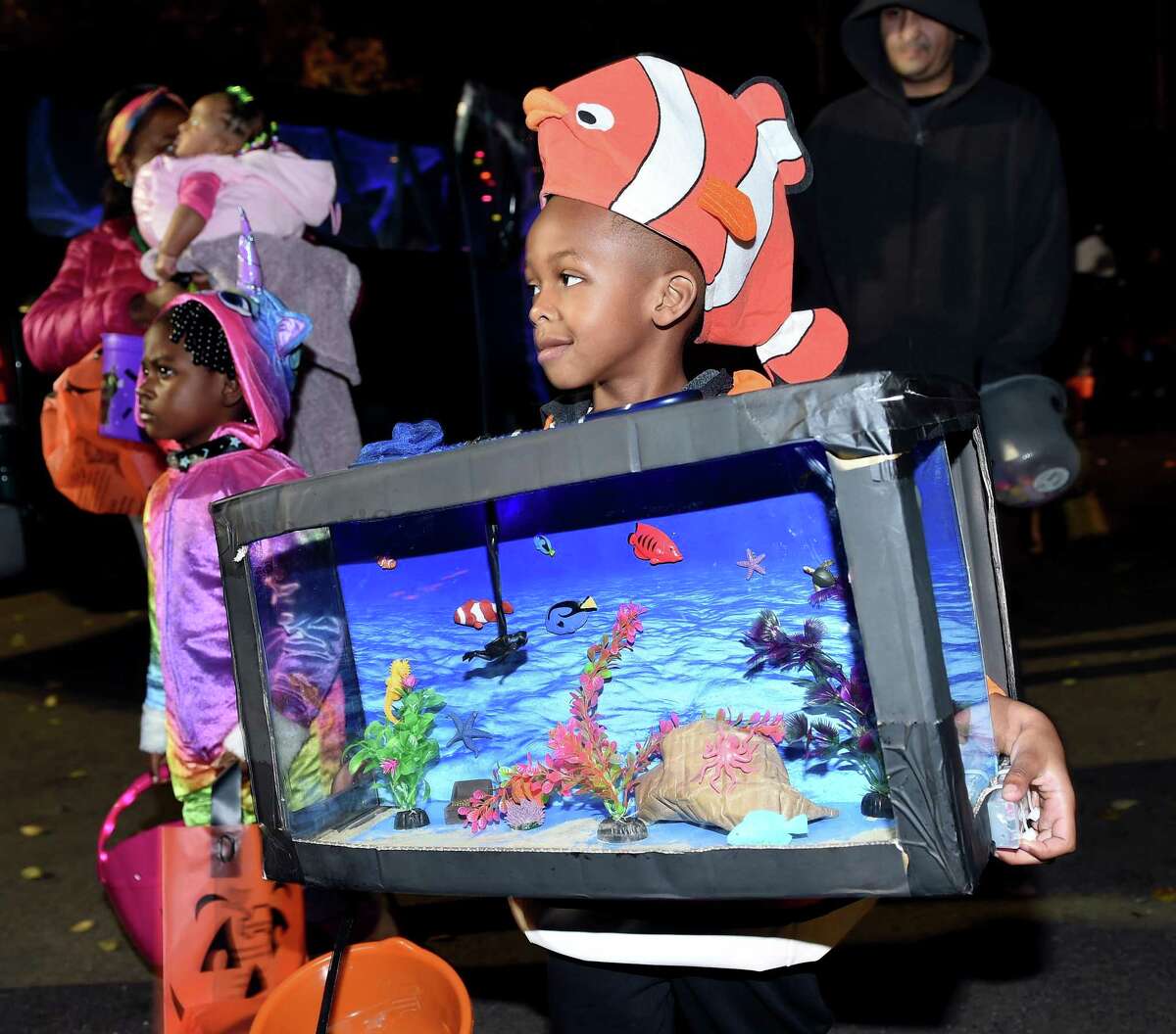 T.J. Relaford, 5, of Hamden, dressed as an aquarium gathers candy at the Halloween Trunk or Treat event at Edgewood Park in New Haven on Wednesday.