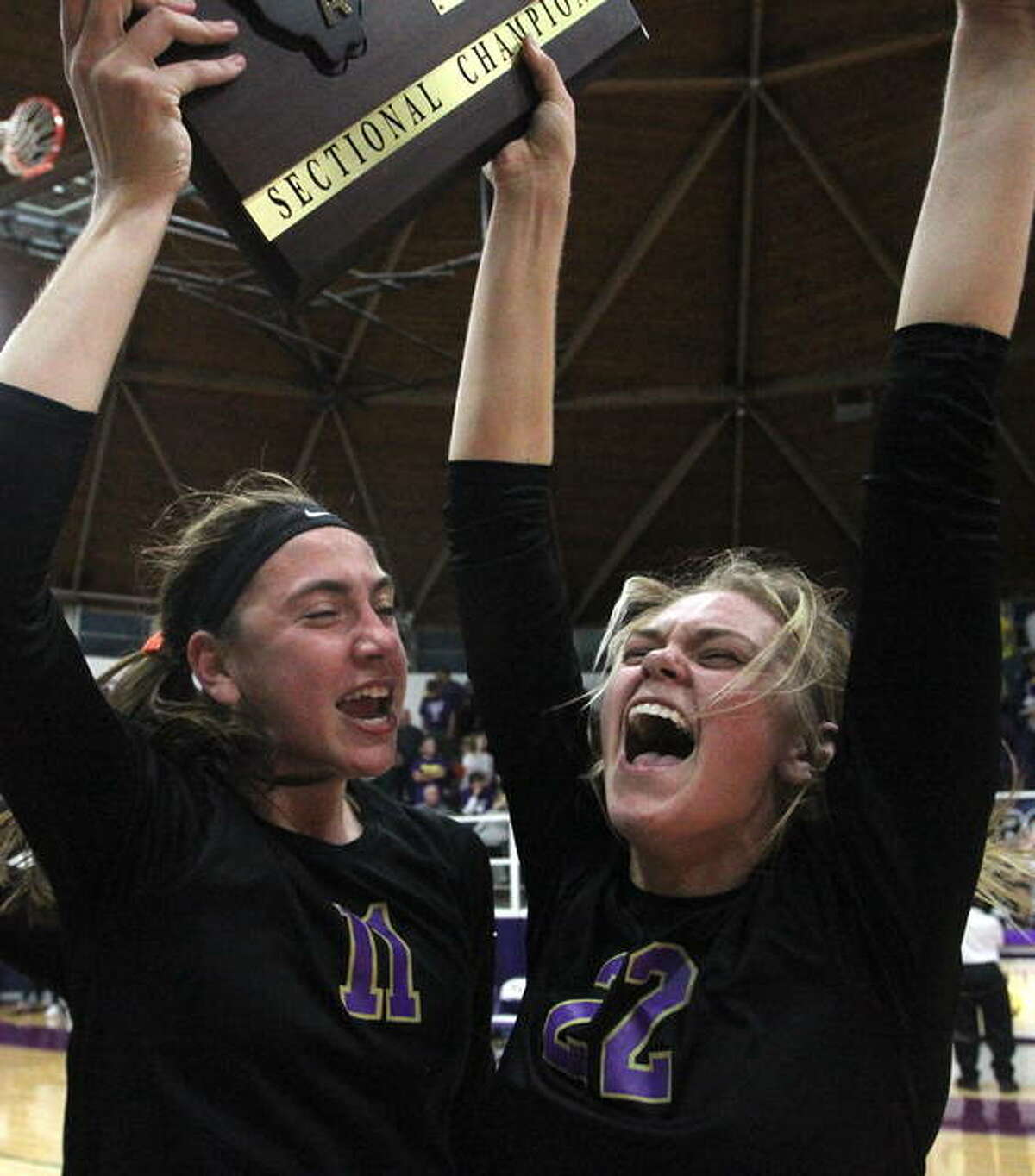 Routt’s Annika Black (left) and Addie Huey sing the school song as they celebrate the Rockets’ sectional championship victory Wednesday night. Routt beat Mount Pulaski in two games to advance to super-sectionals Friday night.