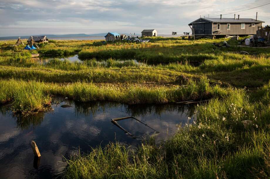 Back to cold things: Permafrost. Like glaciers, permafrost is disappearing and that's causing and lot of problems: Splitting walls, collapsing houses, rollercoaster highways, collapsing coastlines, sinking cemeteries and the release of more CO2 and methane.
"Permafrost covers about 24 percent of the exposed landmass of the Northern Hemisphere—about 9 million square miles. It is found at high latitudes and high altitudes, mainly in Siberia, the Tibetan Plateau, Alaska, Northern Canada, Greenland, parts of Scandinavia and Russia," explains Columbia University's Earth Institute.
However, the institute explains, "the Arctic is warming twice as fast as the rest of the planet, at a rate of temperature change that has not been observed in at least the last 2,000 years. ... (In 2016) permafrost temperatures in the Arctic were the warmest ever recorded. In Alaska, permafrost temperatures have warmed as much as 2˚C in the last few decades. ... with every 1˚C increase in temperature, 1.5 million square miles of permafrost could be lost through thawing."
Photo: Newtok homes are seen situation amongst ponds and tall grass on July 3, 2015 in Newtok, Alaska. Newtok is one of several remote Alaskan villages that is being forced to relocate due to warming tempertures which is causing the melting of permafrost, widening of rivers and the erosion of land and coastline. Photo: Andrew Burton/Getty Images