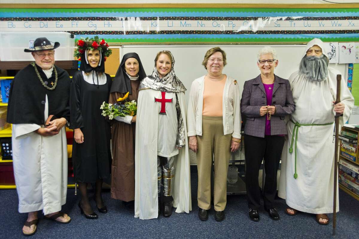 From left, Chuck Zemanek dressed as St. Damien of Molokai, Kristi Galus dressed as St. Rose of Lima, Debbie Smith dressed as St. Teresa of Lisieux, Sarah Selaty dressed as St. Joan of Arc, Terry O'Brien dressed as St. Teresa of Avila, Cathy Richard dressed as St. Gianna Molla and Pete Comardy dressed as St. Peter pose for a photo together before speaking to children at Blessed Sacrament School in celebration of All Saints' Day on Thursday, Nov. 1, 2018. (Katy Kildee/kkildee@mdn.net)