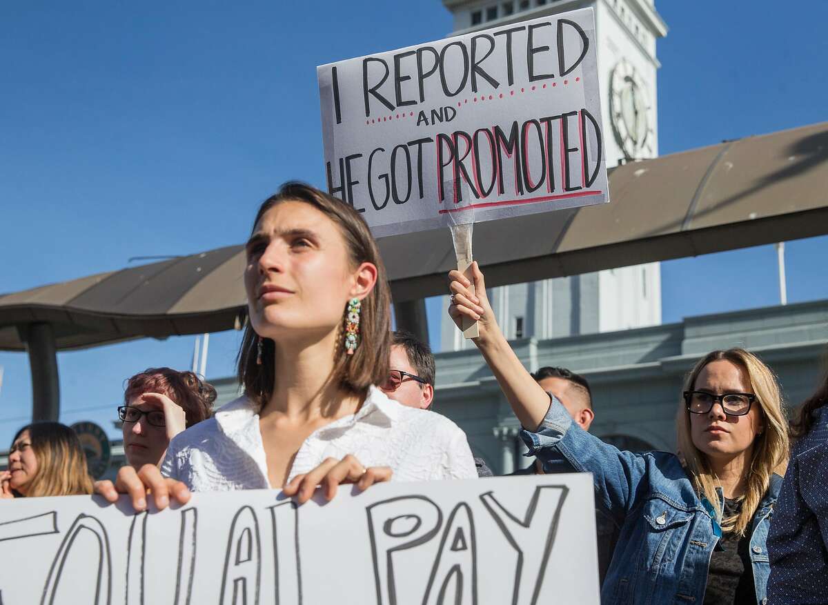 Google employees Lucia Rossazza, left, and Jennifer Brown, right, carry signs while listening to speakers during a rally and company-wide walkout and from their offices in San Francisco, Calif. Thursday, Nov. 1, 2018 highlighting the mishandling by the company of sexual misconduct allegations.