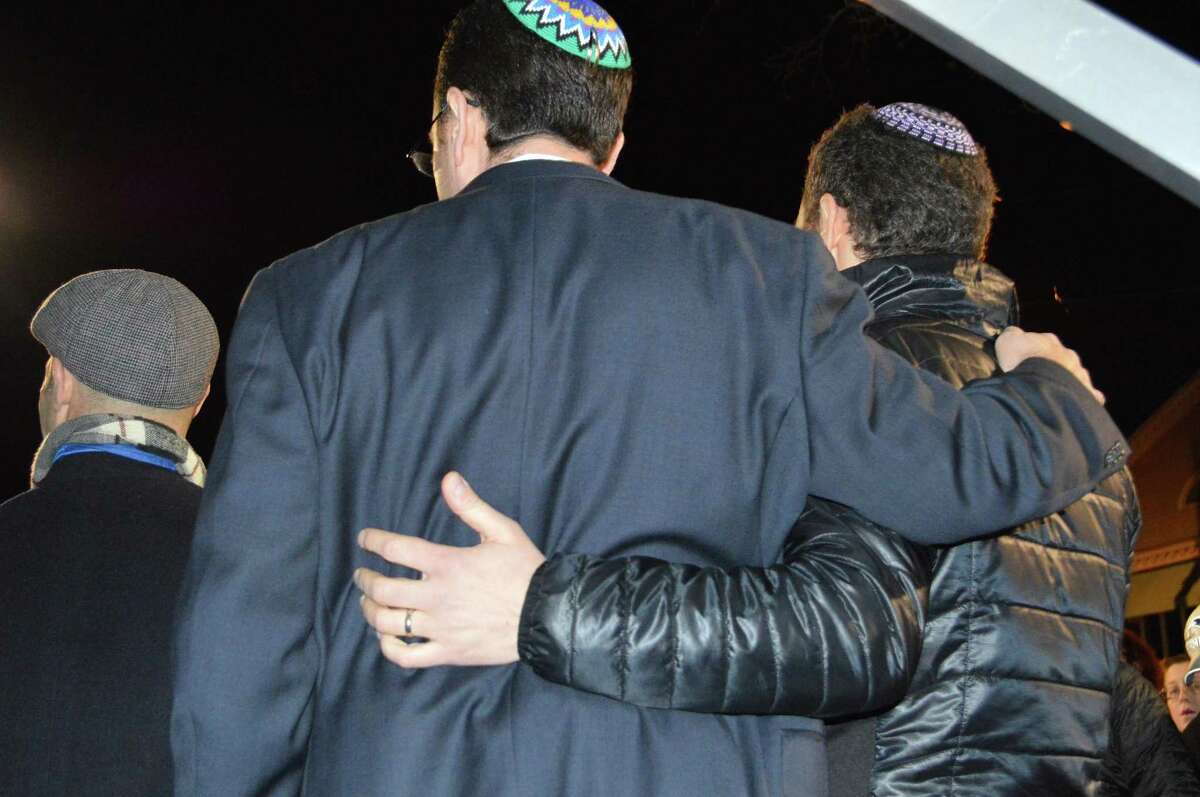 Rabbi Michael Friedman of Temple Israel, right, and Rabbi Jeremy Wiederhorn of the Conservative Synagogue embrace the Hanukkah spirit of family and community at the menorah-lighting ceremony downtown.