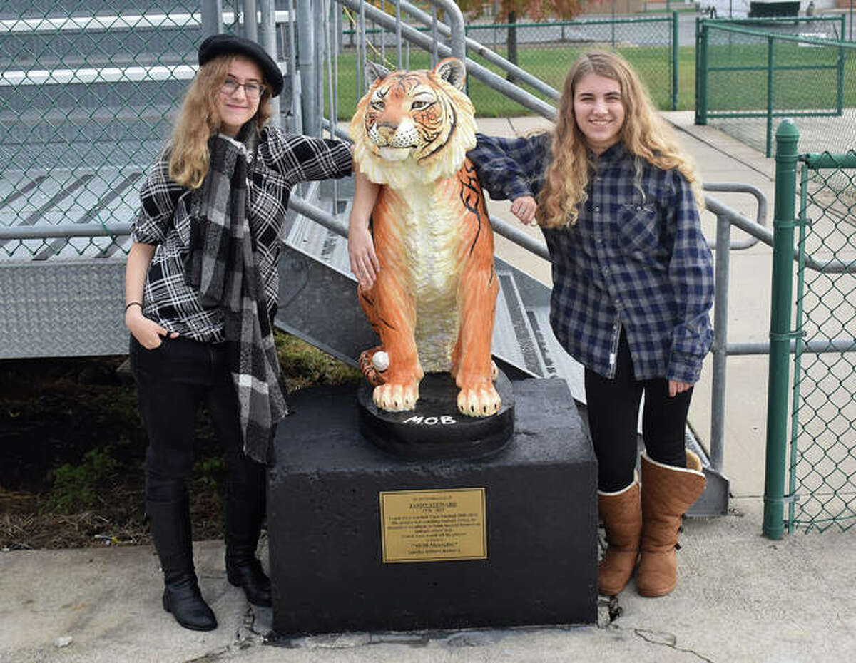 Edwardsville High School seniors Kia Smidt, left, and Grace Becker stand next to the tiger statue they painted last school year. The statue is near the south end zone of the football field.