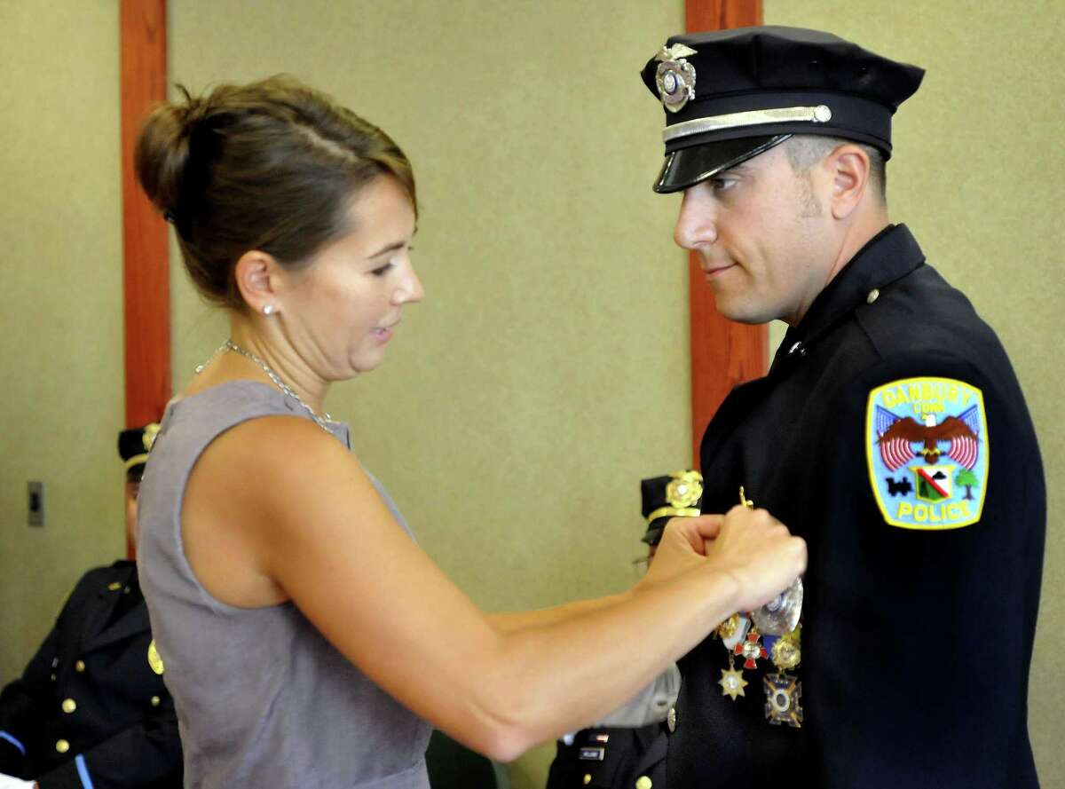 Tanya LaBonia performs the traditional pinning ceremony as her husband, Len LaBonia, is promoted to detective in the Danbury Police Department Thursday, Sept. 15, 2011.