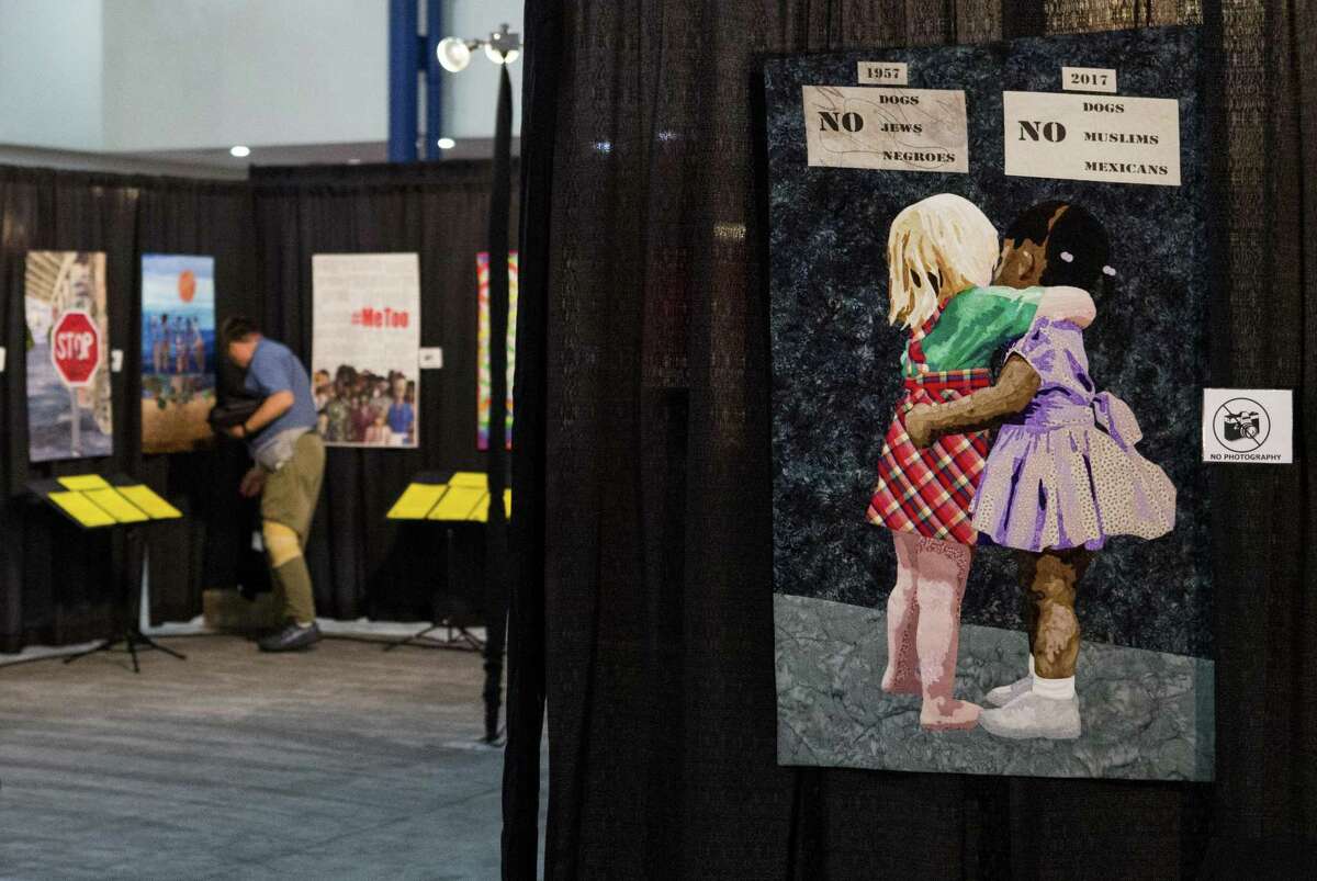 Harmon Everett walks through the OURstory exhibit as he helps set up of the 2018 International Quilt Festival at the George R. Brown Convention Center. The quilt titled "Color Blind," in the foreground, is part of the powerful OURstory exhibit that tackles human rights subjects through art quilts.