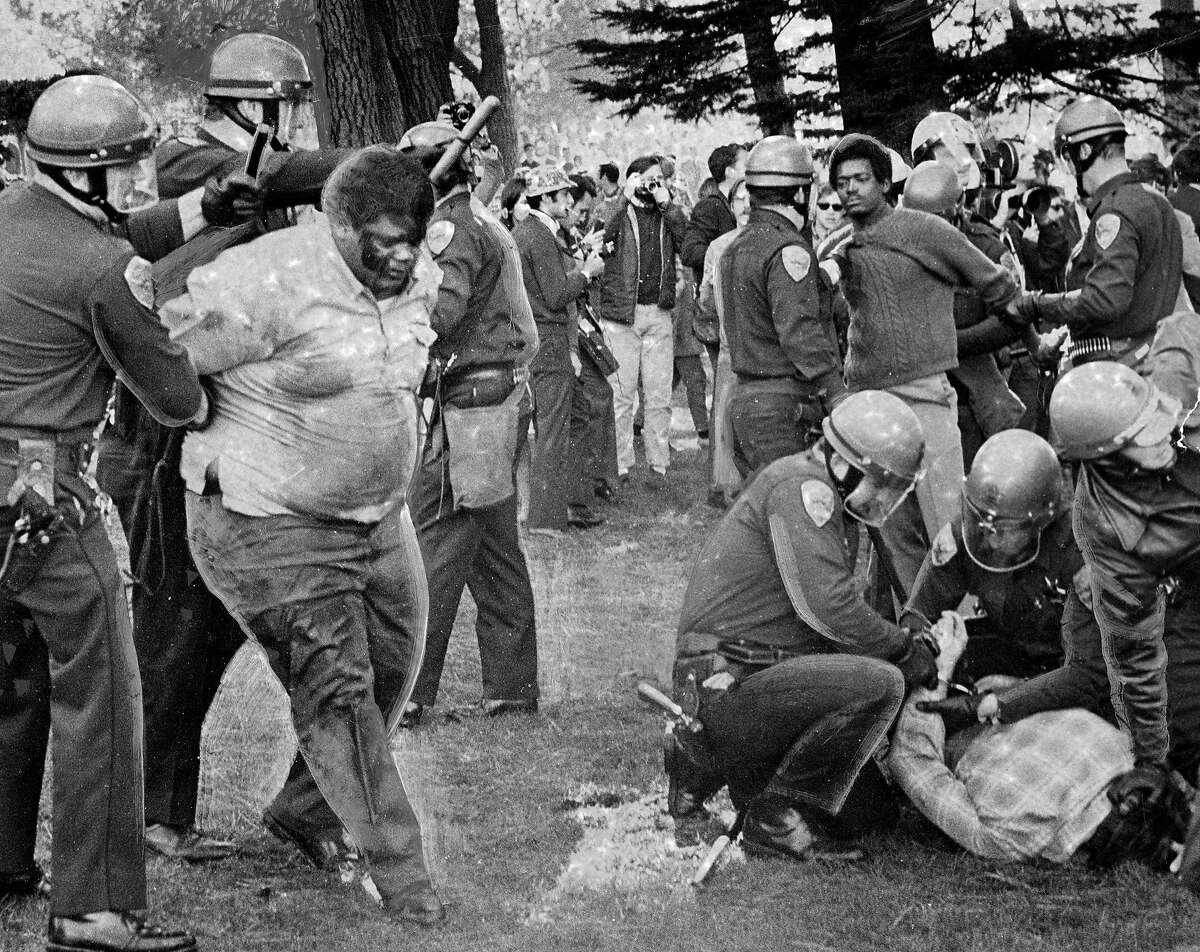 1968年12月3日，一队警察闯入支持关闭旧金山州立大学罢工的示威者中。唐纳德·麦卡利斯特正被两名警官带走照片摄于1968年12月8日，《这个世界》第5页