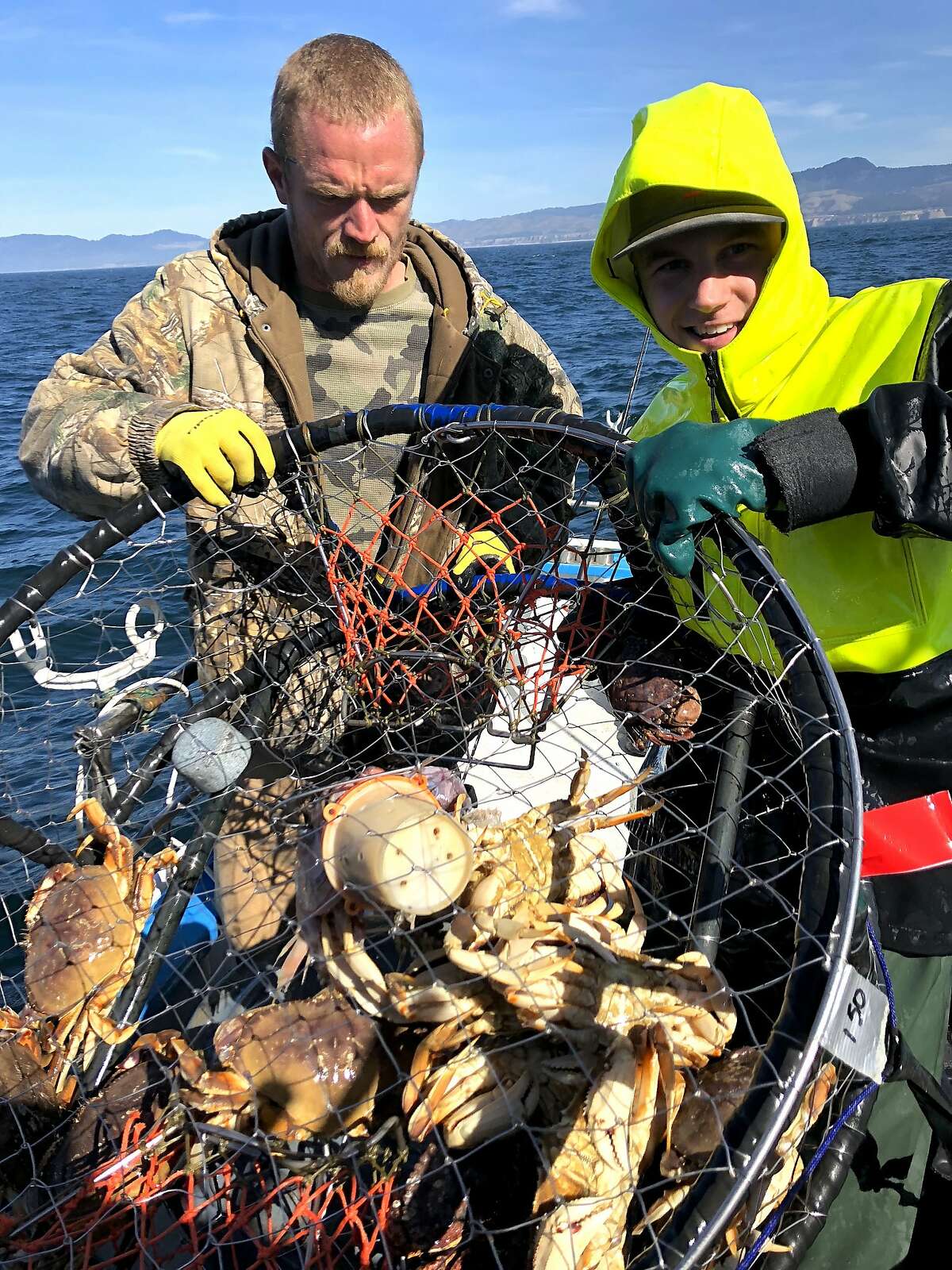 Dennis Brown, on left, and Dillon Watkins, hoist the first crab pot of the season on the Huli-Cat ouf of Half Moon Bay and found 12 Dungeness crab, 2 rock crabs -- en route to a limit opener for all boats out of Bay Area harbors.