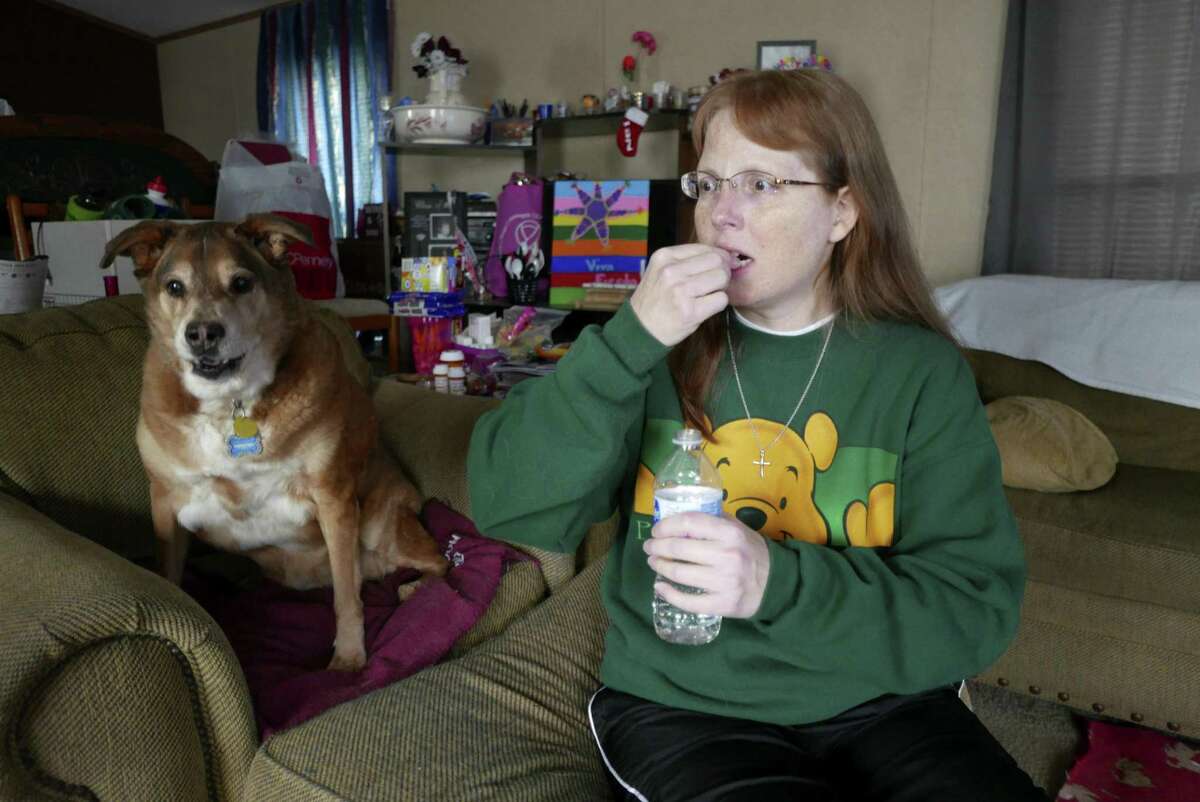 Jennifer Nelms, a cancer survivor who depends on an opioid medication to function, takes her pill on Tuesday, Oct. 16, 2018. She sits with her dog, Priscilla, whom she credits with helping detect her cancer.