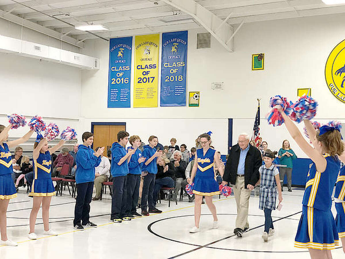 Our Lady Queen of Peace students escort a veteran to the front of the school’s gymnasium Tuesday during OLQP’s annual Veterans Day Thank You Program. More than 30 veterans were recognized at the Bethalto school’s ceremony.