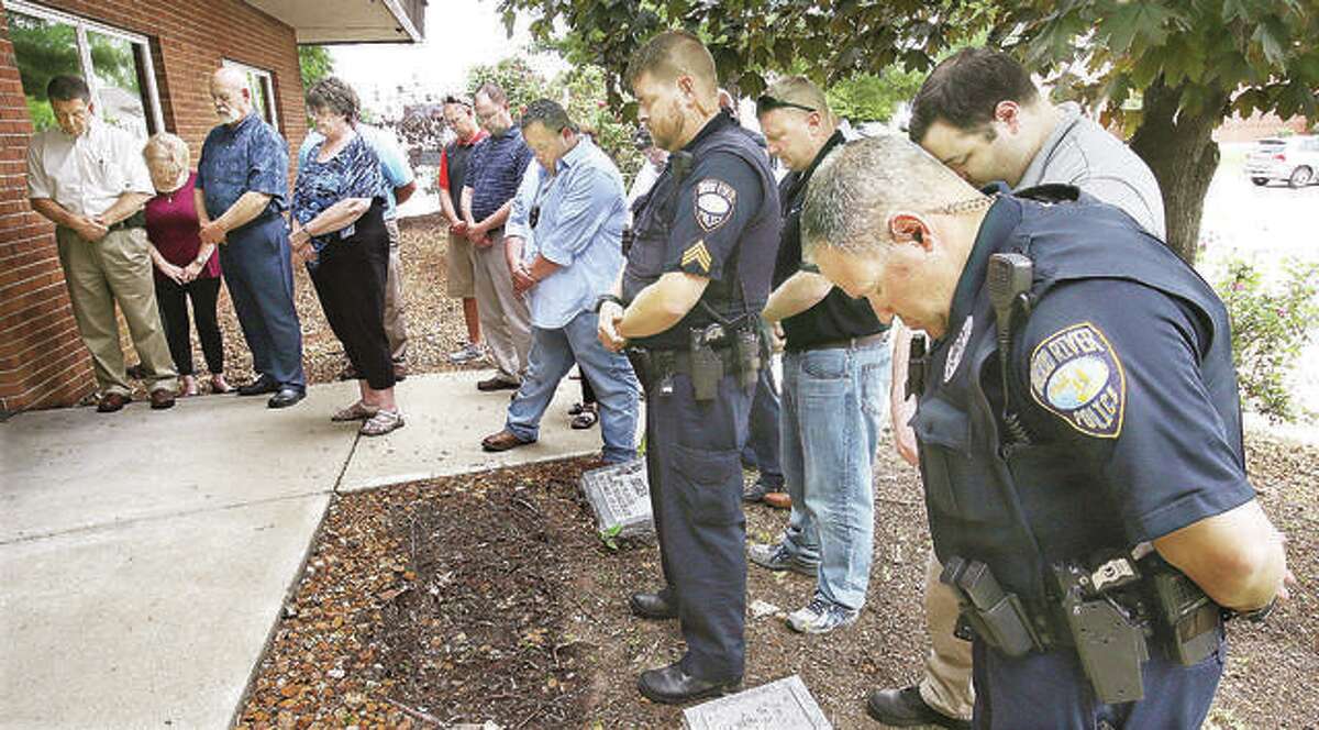 Wood River police officers and city officials bow their heads during a prayer at a brief ceremony held in front of the Wood River Police station this past May to honor the two Wood River officers who have died in the line of duty over the years. The Wood River Police Association will have a charity raffle to raise money for an Officer Down Memorial in front of the Wood River Police Department to honor the two fallen officers.