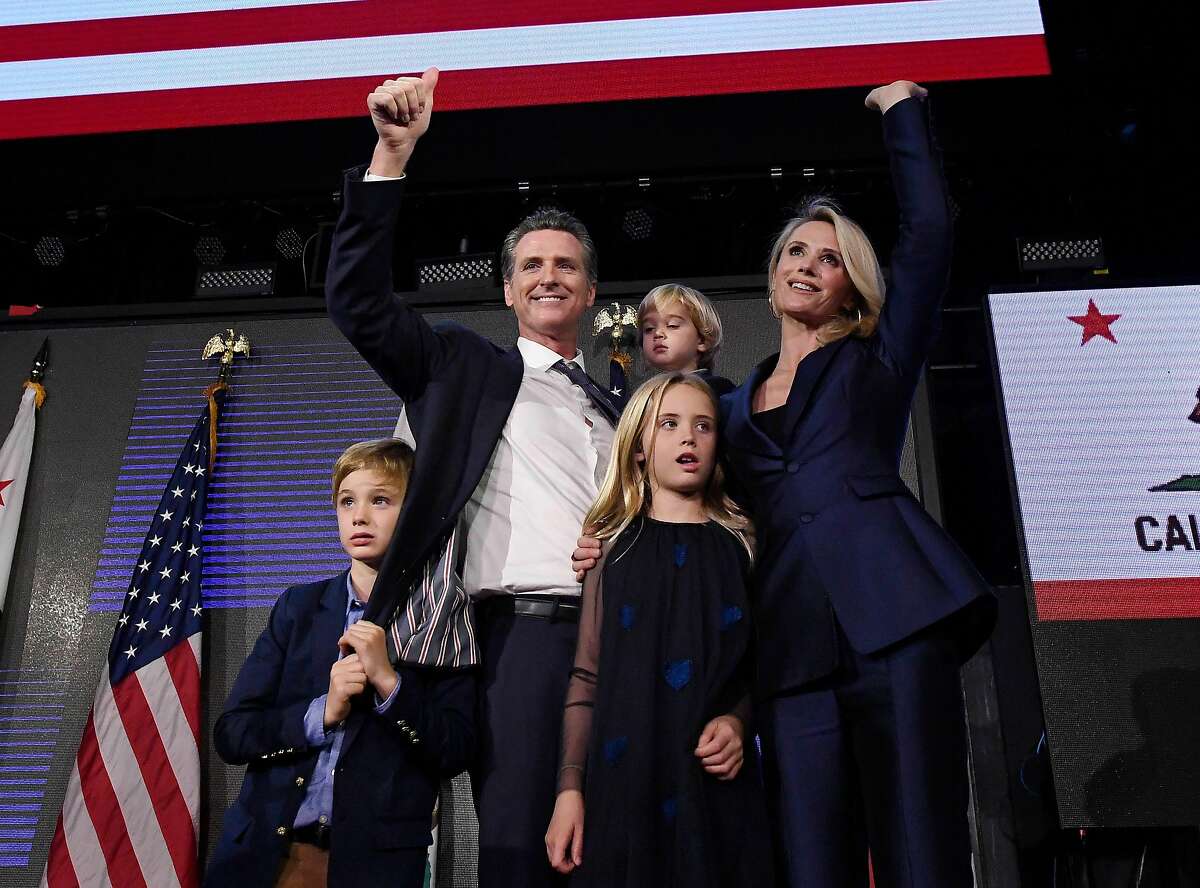 Democratic gubernatorial candidate Gavin Newsom holding his son Dutch, 2, and standing with his son Hunter, 7, wife Jennifer Siebel Newsom and daughter Montana, 9, as he waves to supporters.