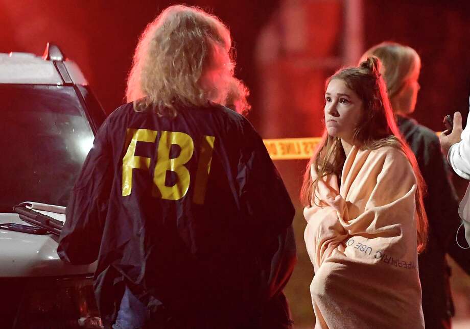 An FBI agent talks to a potential witness as they stand near the scene Thursday, Nov. 8, 2018, in Thousand Oaks, Calif. where a gunman opened fire Wednesday inside a country dance bar crowded with hundreds of people on