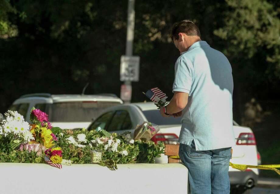 Brian White places a U.S. flag with a flower near the scene of a mass shooting Thursday, Nov. 8, 2018, in Thousand Oaks, Calif., after a gunman opened fire Wednesday evening inside a country music bar, killing multiple people including a responding sheriff's sergeant. Photo: Ringo H.W. Chiu, AP / Copyright 2018 Associated Press. All rights reserved.