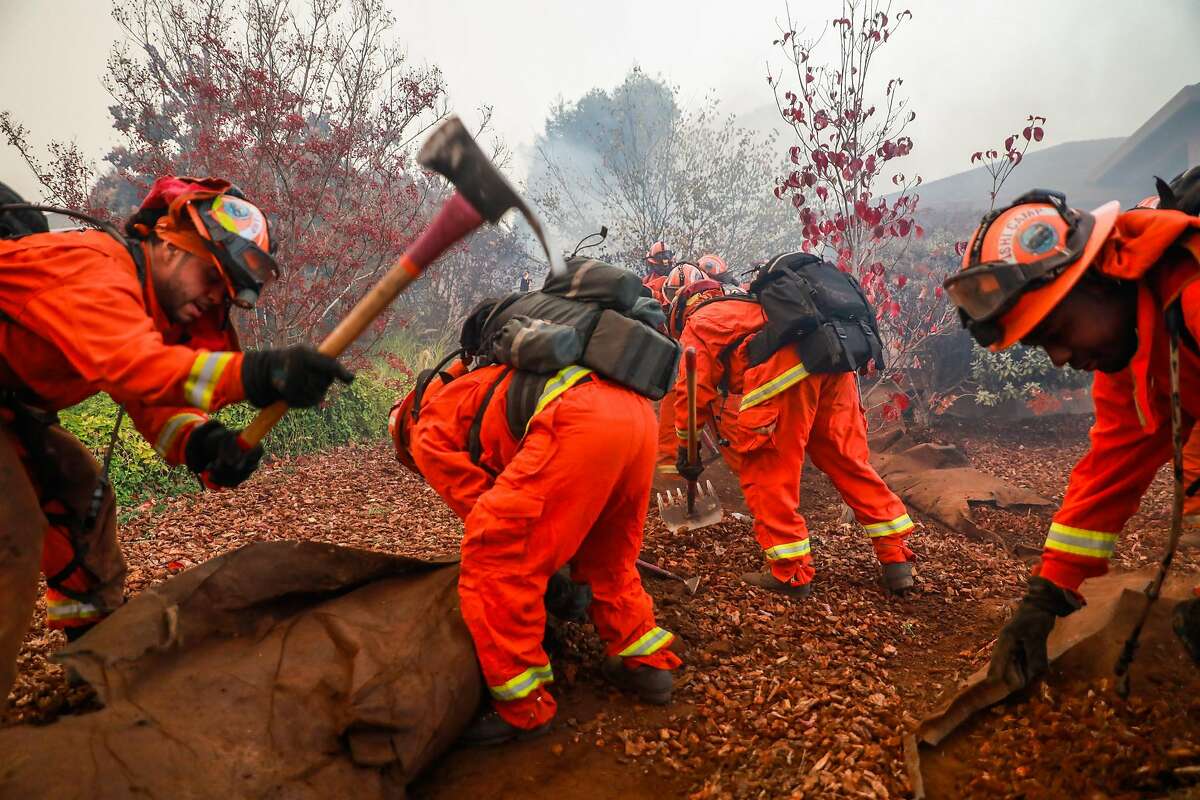 Inmate firefighters dig a trench to try and save a house off of Pentz Road during the Camp Fire in Paradise, California, on Thursday, Nov. 8, 2018.