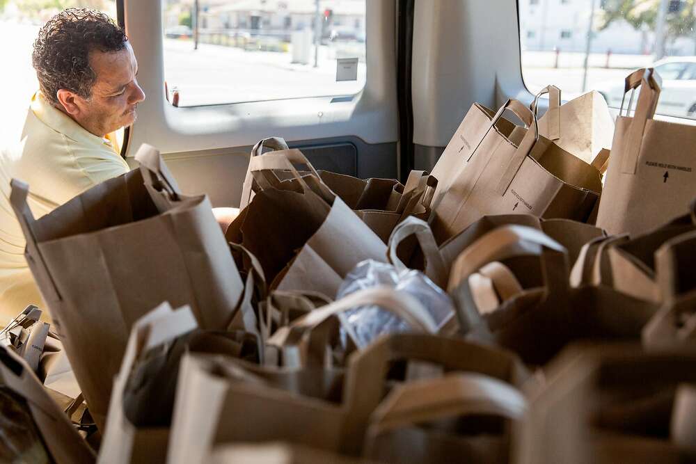 Man reaching into a van filled with paper bags