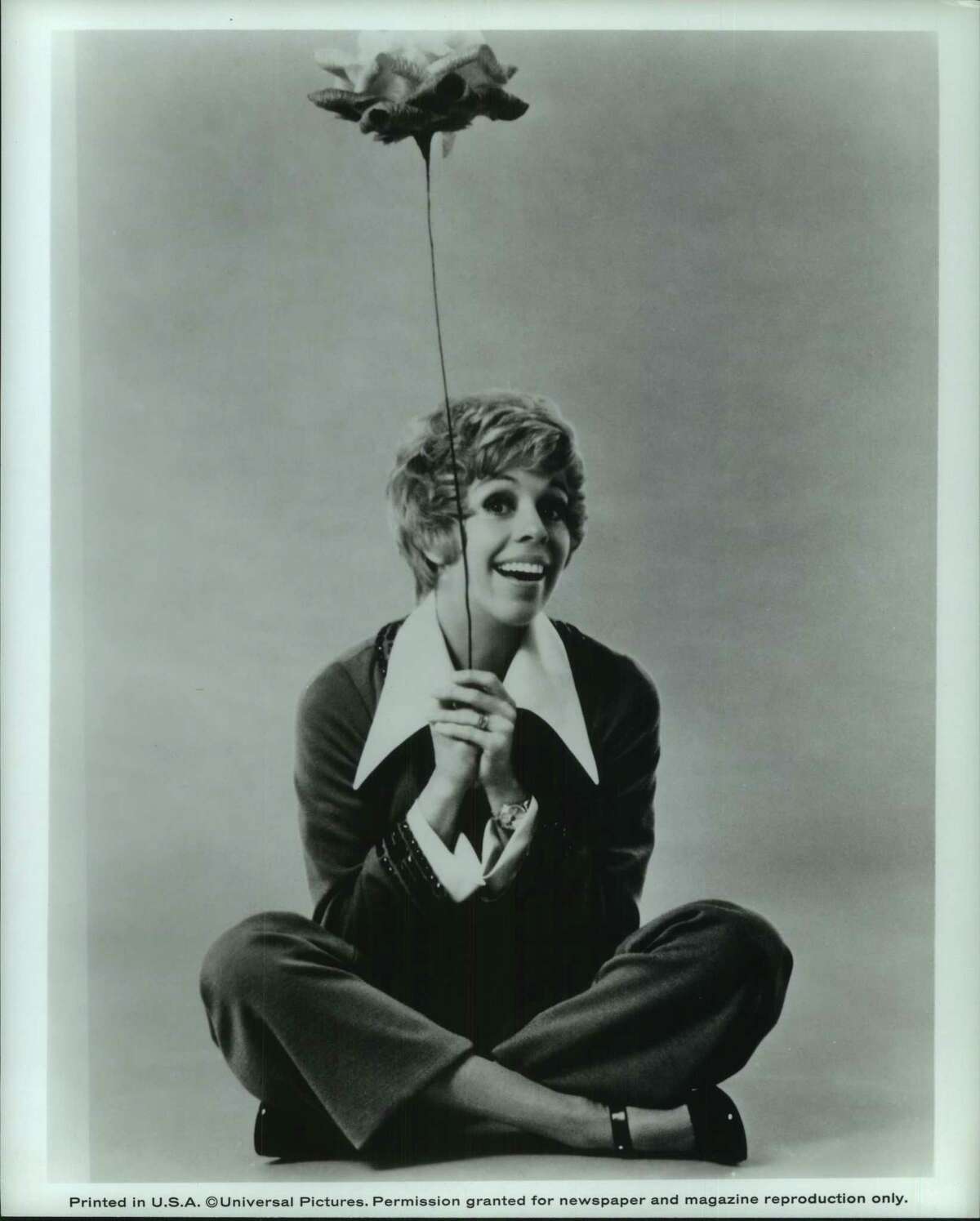 Smiling Carol Burnett Sitting Cross-Legged Holding Flower