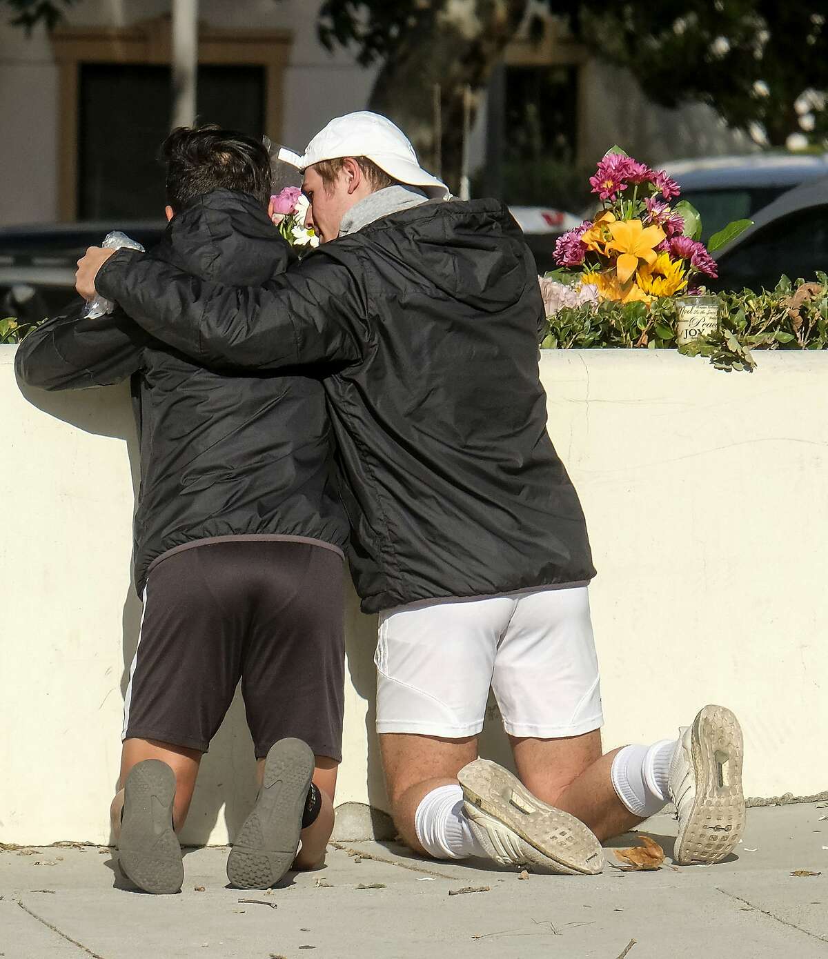 People place flowers near the scene of a mass shooting Thursday, Nov. 8, 2018, in Thousand Oaks, Calif., after a gunman opened fire Wednesday evening inside a country music bar, killing multiple people including a responding sheriff's sergeant. (AP Photo/Ringo H.W. Chiu)