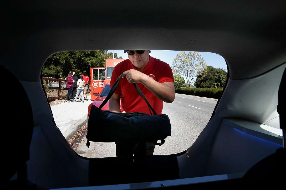 Zume pizza delivery driver Gustavo Vega loads up a pizza for delivery in Palo Alto, Calif., Ca., on Tues. April 17, 2018. Zume Pizza uses robotic pizza-makers and smart ovens inside a truck to deliver cooked-to-order pizzas to customers.