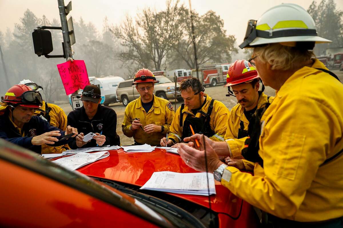 Firefighters get ready for the day as they have a meeting on Skyway after the Camp Fire tore through Paradise, Calif. on Saturday, Nov. 10, 2018.