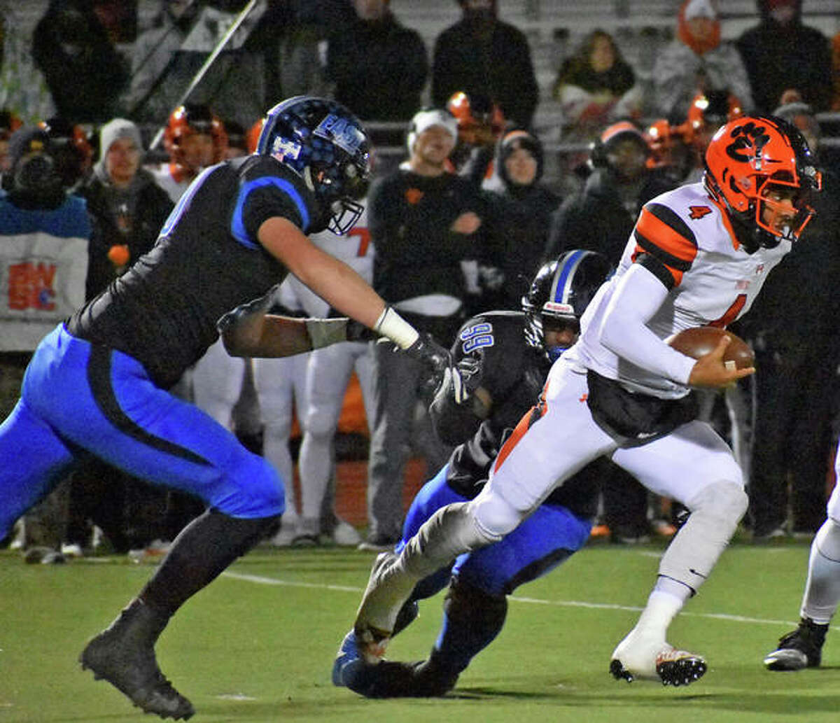 Edwardsville quarterback Kendall Abdur-Rahman, right, breaks a tackle during a 10-yard run in the first quarter against Lincoln-Way East on Saturday in a quarterfinal game in Frankfort.
