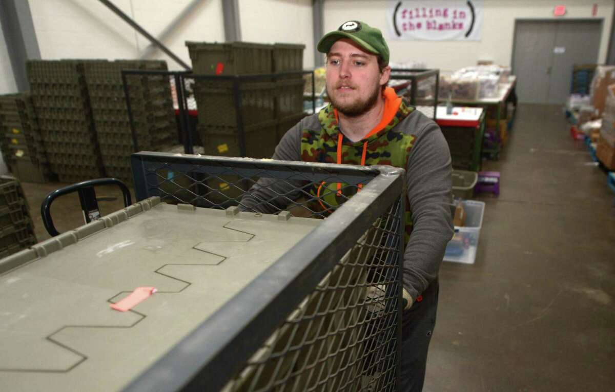 Hunter Van Veghel, delivery driver for Filling in the Blanks, loads up his truck Thursday at their Main Avenue location in Norwalk. Filling In The Blanks is a nonprofit that fights against childhood hunger by bringing food to schools. The meals are held by social workers or teachers until Friday afternoon and then given to students who need something to eat on the weekends.