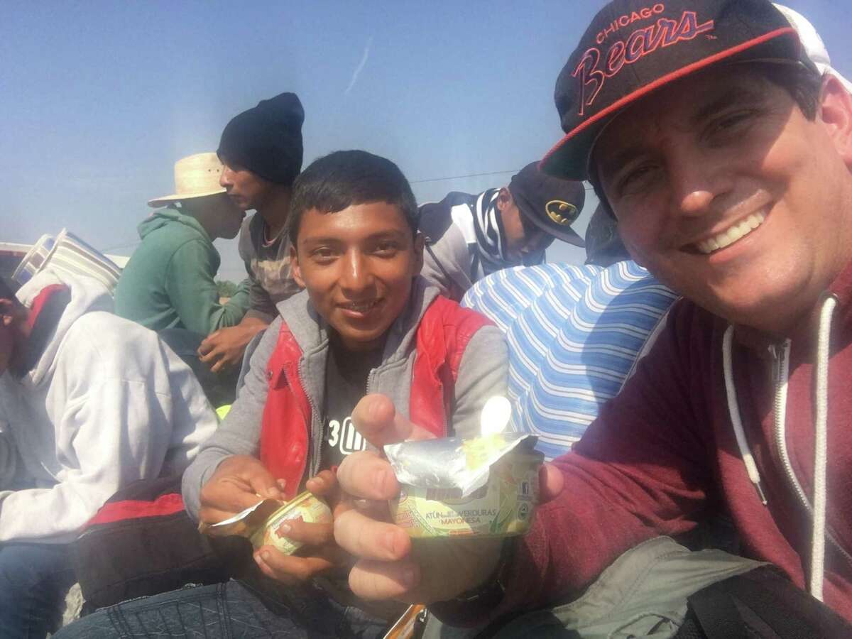 San Antonio clergyman Gavin Rogers shared a meal with a Central American youth on the caravan over the weekend as they rode atop a flatbed trailer whose driver offered a free lift to the travelers.