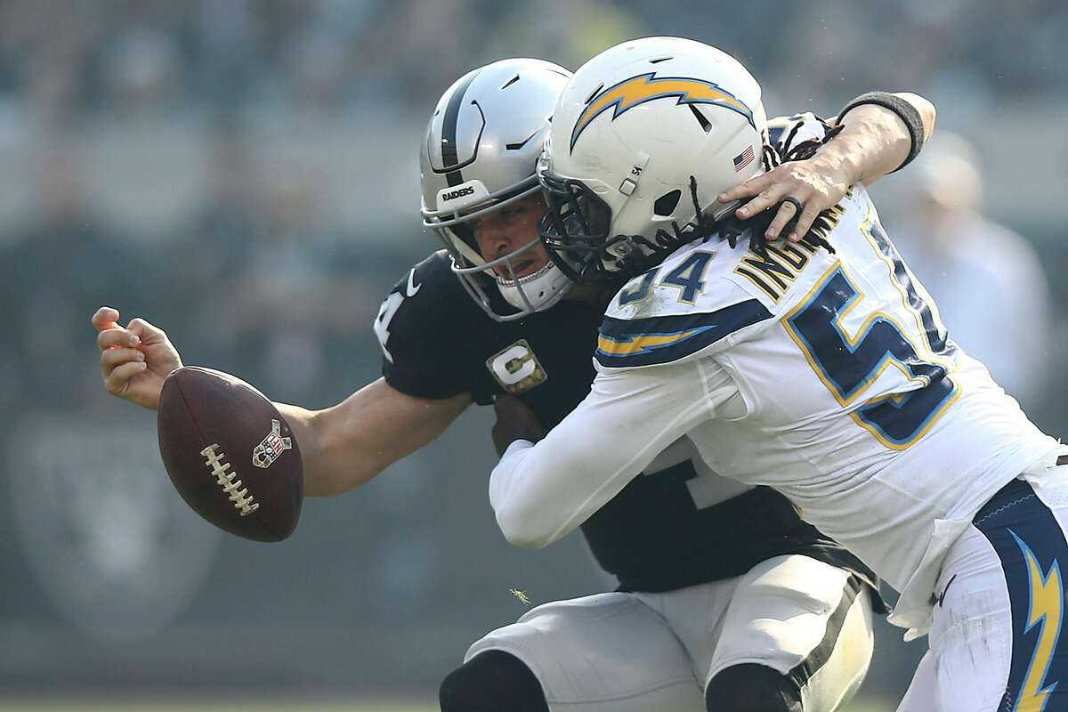 CORRECTED VERSION - OAKLAND, CA - NOVEMBER 11: Derek Carr #4 of the Oakland Raiders fumbles the ball after a hit by Melvin Ingram #54 of the Los Angeles Chargers during their NFL game at Oakland-Alameda County Coliseum on November 11, 2018 in Oakland, California. (Photo by Ezra Shaw/Getty Images)