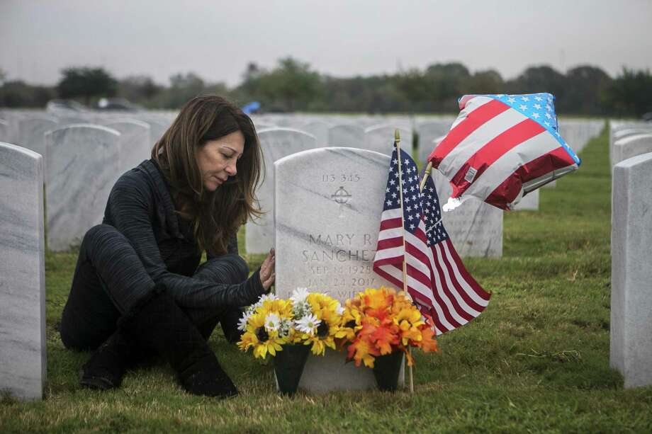 Eva Sanchez delicately touches the tombstone of her stepfather, Carlos Sanchez, and her stepmother, Mary Sanchez, as she travels to the shrine to decorate them at the Fort Sam Houston National Cemetery on Sunday 11 November 2018. Sanchez raises the gravestone by saying often 