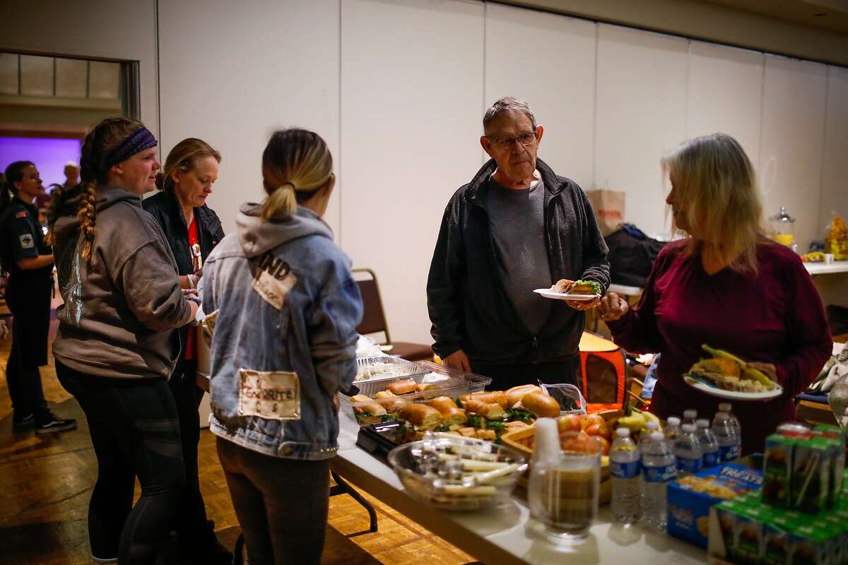 Camp Fire evacuee Norm Wright (center) gets a bite to eat for lunch at the Red Cross shelter in Chico, California, on Friday, Nov. 9, 2018.