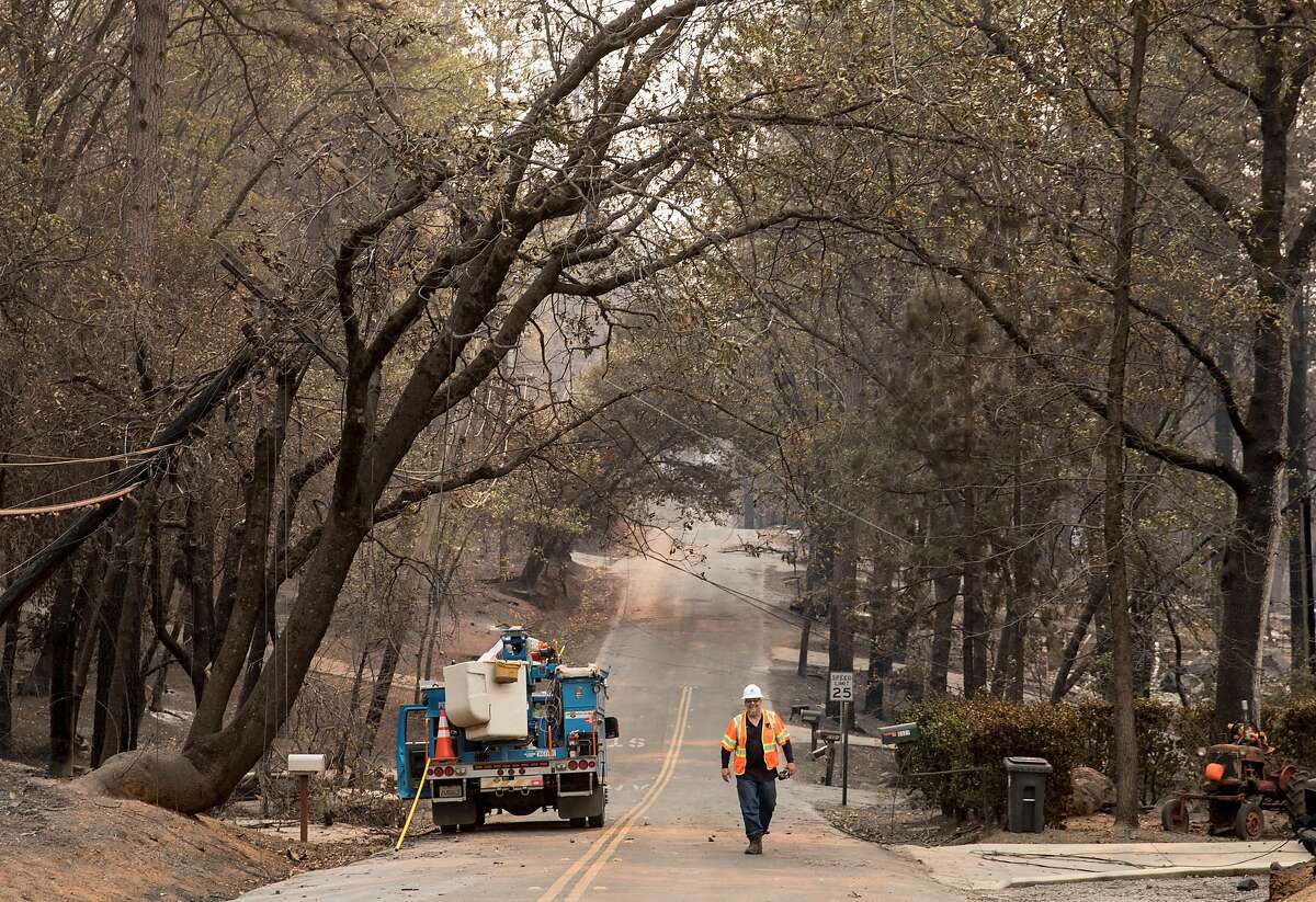 A PG&E employee walks down Edgewood Lane Sunday, Nov. 11, 2018 after the Camp Fire ripped through the town of Paradise, Calif.