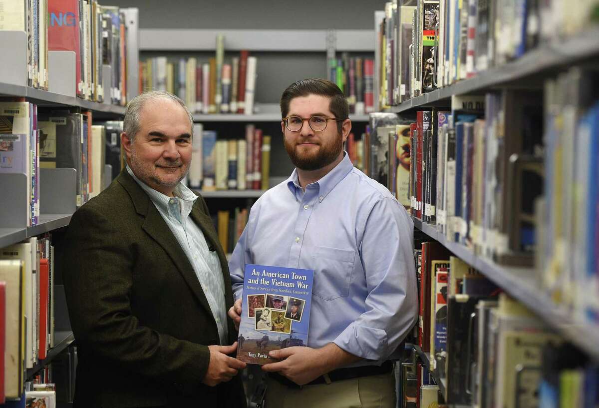 Stamford resident Tony Pavia and his son, Matt Pavia, a teacher at Darien High School, show their new book “An American Town and the Vietnam War” during a reception at Darien High School in Darien on Monday. The book documents stories of Stamford veterans and their service in the Vietnam War.
