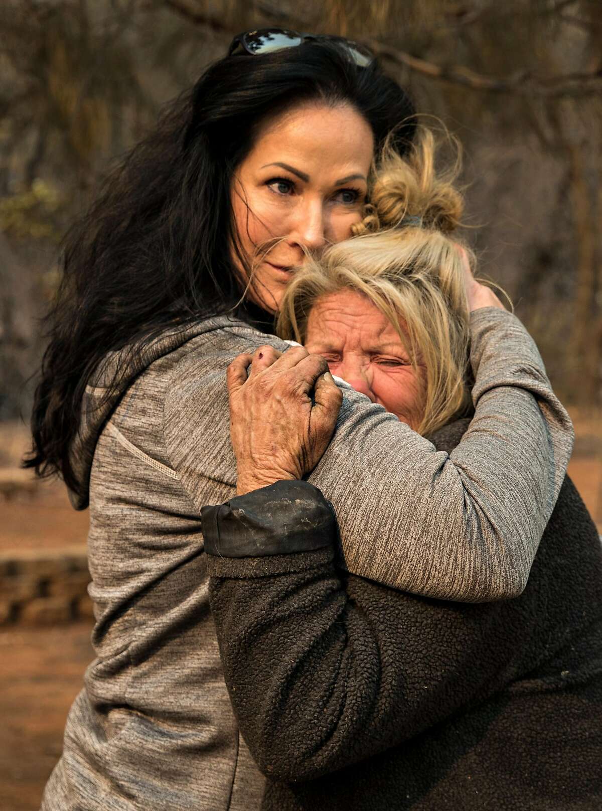 2018年11月11日，动物志愿者塔玛拉·休斯顿(左)在凯茜·法伦的家外安慰她。法伦在加州天堂镇的营火中幸存下来，当时她躲在埃奇伍德巷的家中。