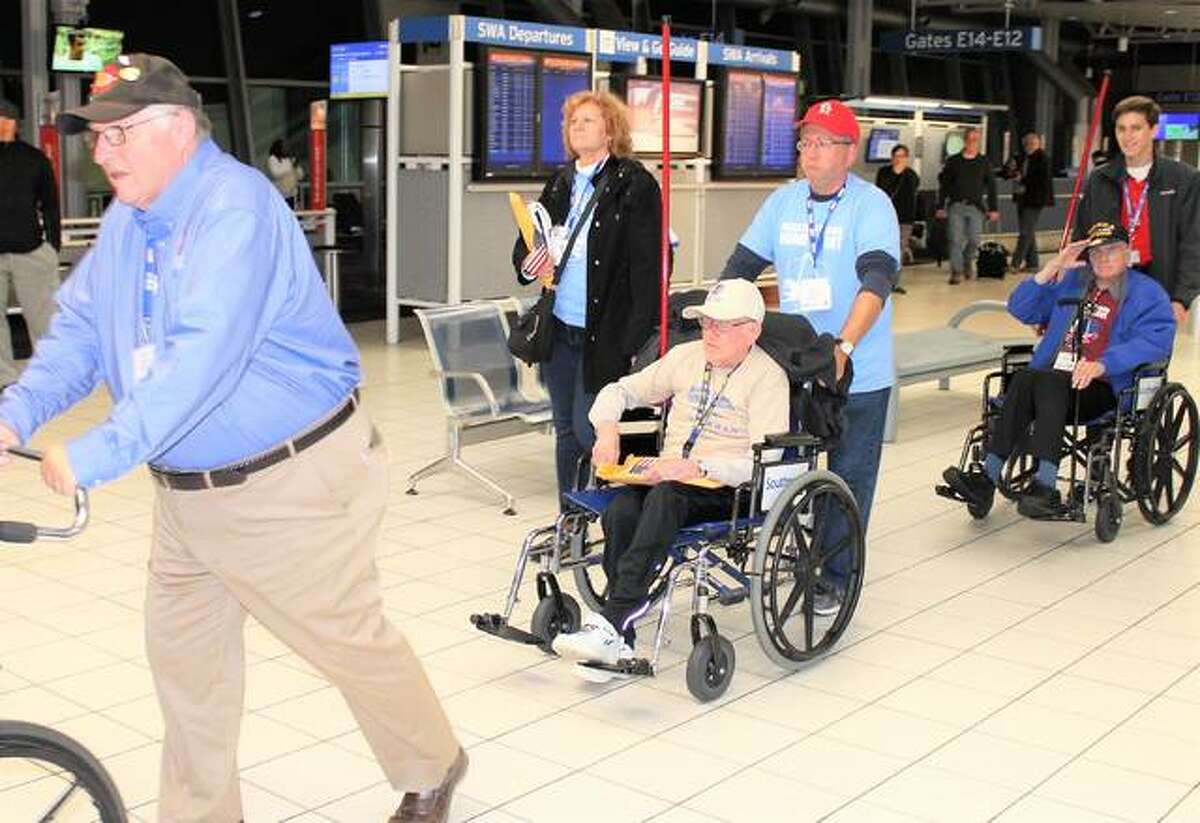 Bob White, of Edwardsville, a veteran of both World War II and the Korean War, center, is escorted by his son, David White, through Lambert International Airport on Saturday after taking part in a Greater St. Louis Honor Flight to Washington, D.C.
