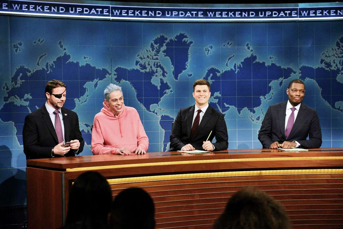 In this Nov. 10, 2018 photo provided by NBC, Lt. Com. Dan Crenshaw, from left, a congressman-elect from Texas, Pete Davidson, Anchor Colin Jost, and Anchor Michael Che appear during Saturday Night Live’s "Weekend Update" in New York. Davidson made his apologies to Crenshaw whose appearance he mocked, saying Crenshaw “deserves all the respect in the world.” (Will Heath/NBC via AP)