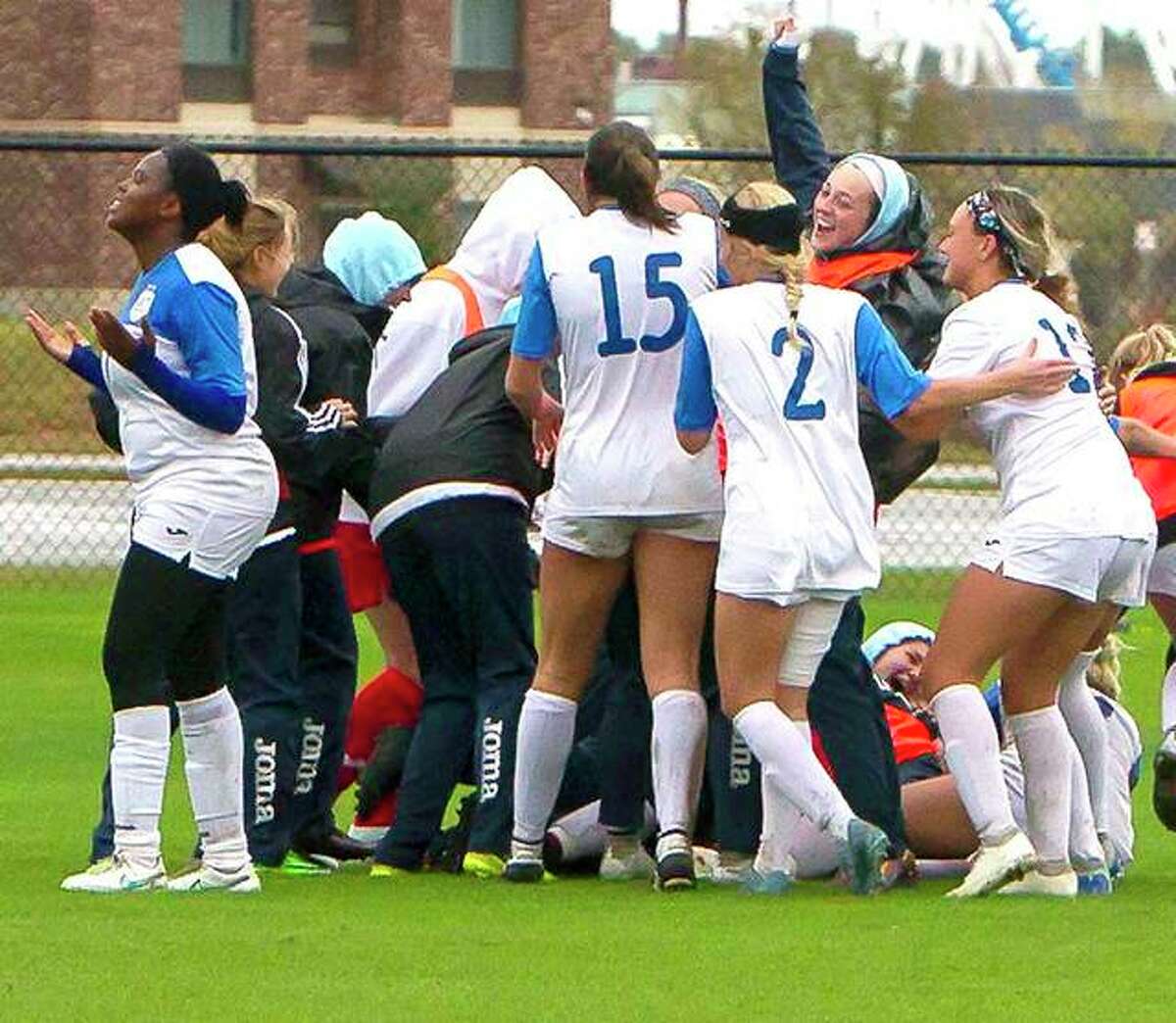 The Lewis and Clark Community College women’s soccer players mob teammate Senate Letsie (hidden) as they celebrate their 3-2 overtime victory over Butler Community College Tuesday at the NJCAA National Tournament in Foley, Ala.