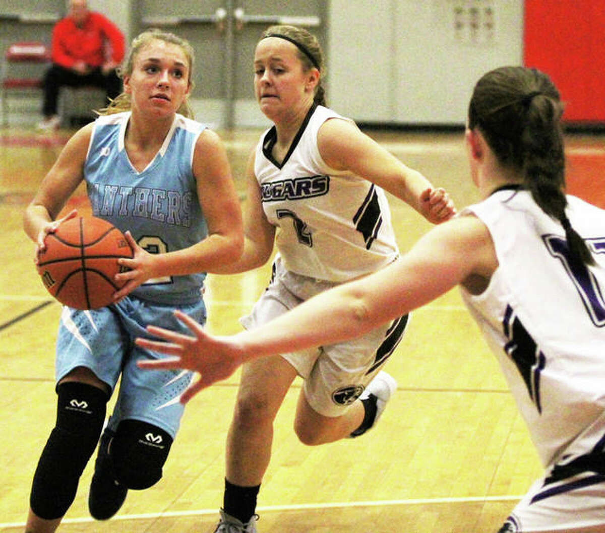 Jersey’s Clare Breden (left) drives past Breese Central’s MiKayla Becker (middle) while another Cougar defends the rim during the Panthers overtime victory Tuesday at the Alton Tourney. Breden led all scorers with 21 points.